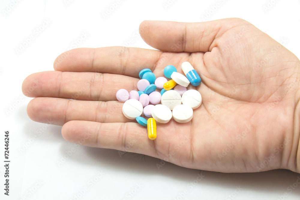 Diferent tablets pills heap mix in hand on white isolated backgr Diferent tablets pills heap mix in hand on white isolated backgr