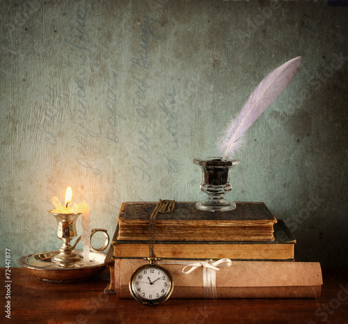 low key image of white Feather, inkwell and ancient books on old