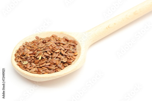 Heap of linseed with wooden spoon on white background