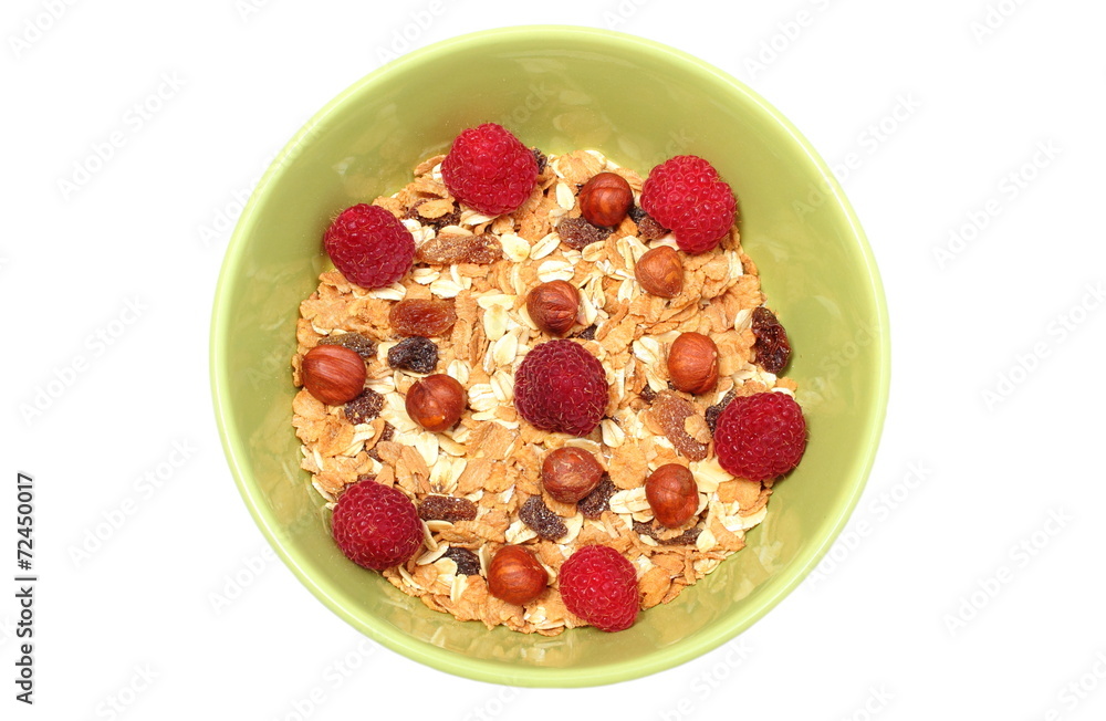 Heap of muesli with hazelnut and raspberries in green bowl Heap of muesli with hazelnut and raspberries in green bowl