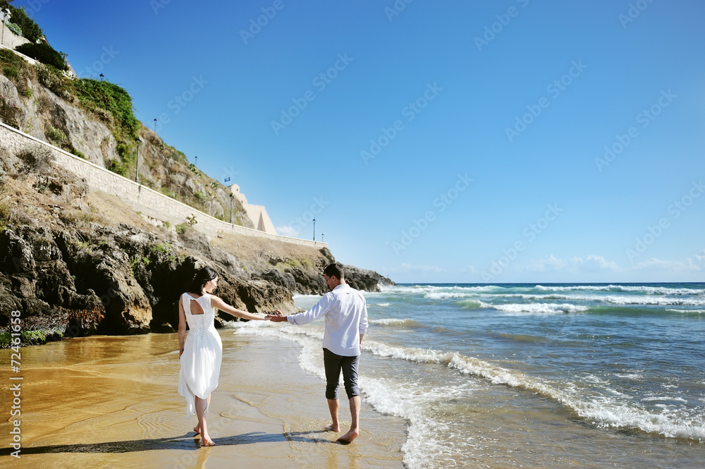 Couple walking on beach together holding hands Couple walking on beach together holding hands
