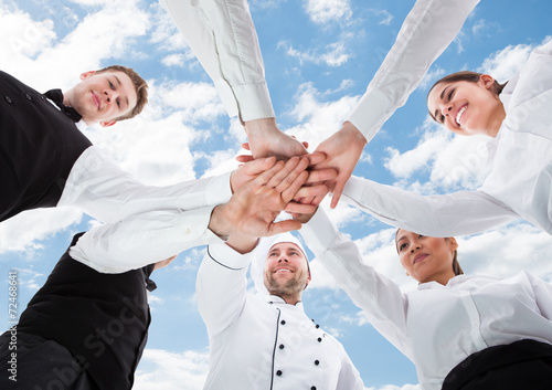 Chef And Waiters Piling Hands Against Sky