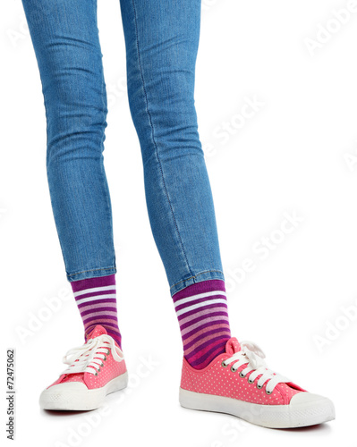 Female legs in colorful socks and sneakers isolated on white