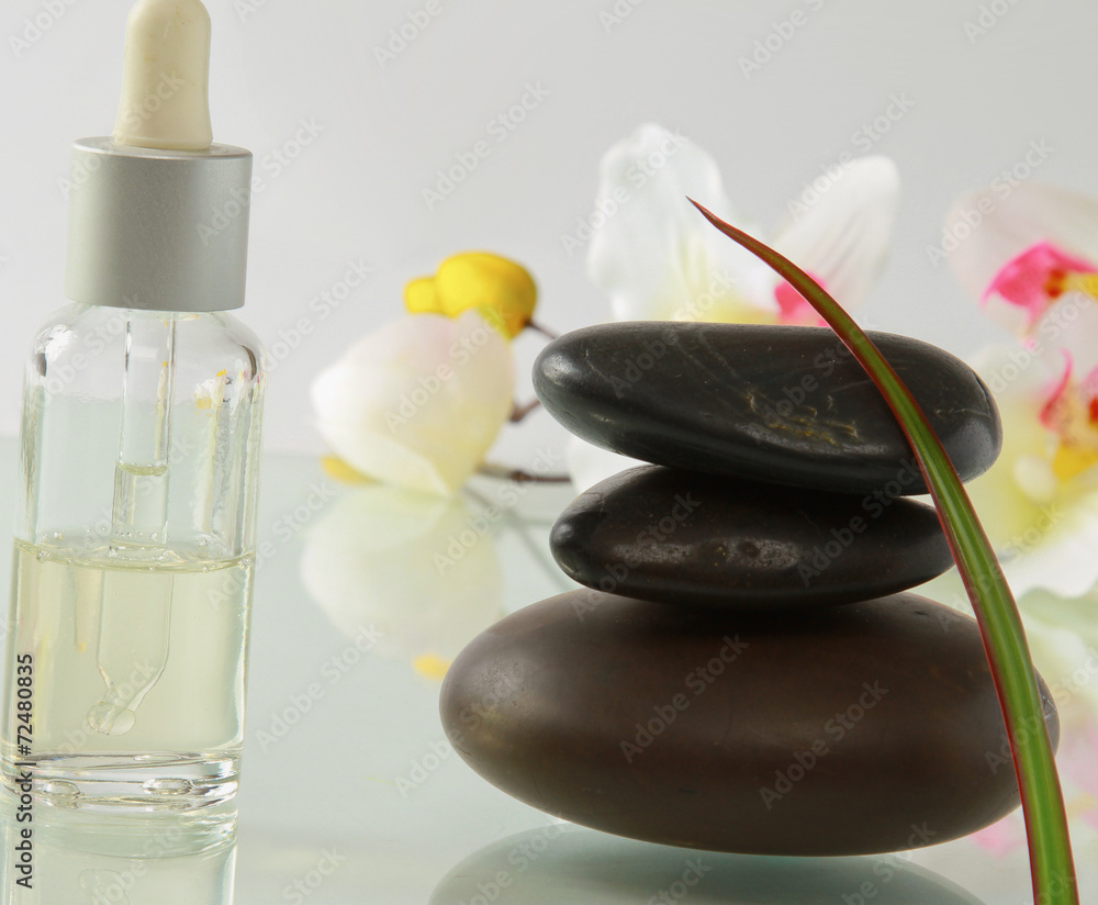 bottles of essential oil and set of stones with flower