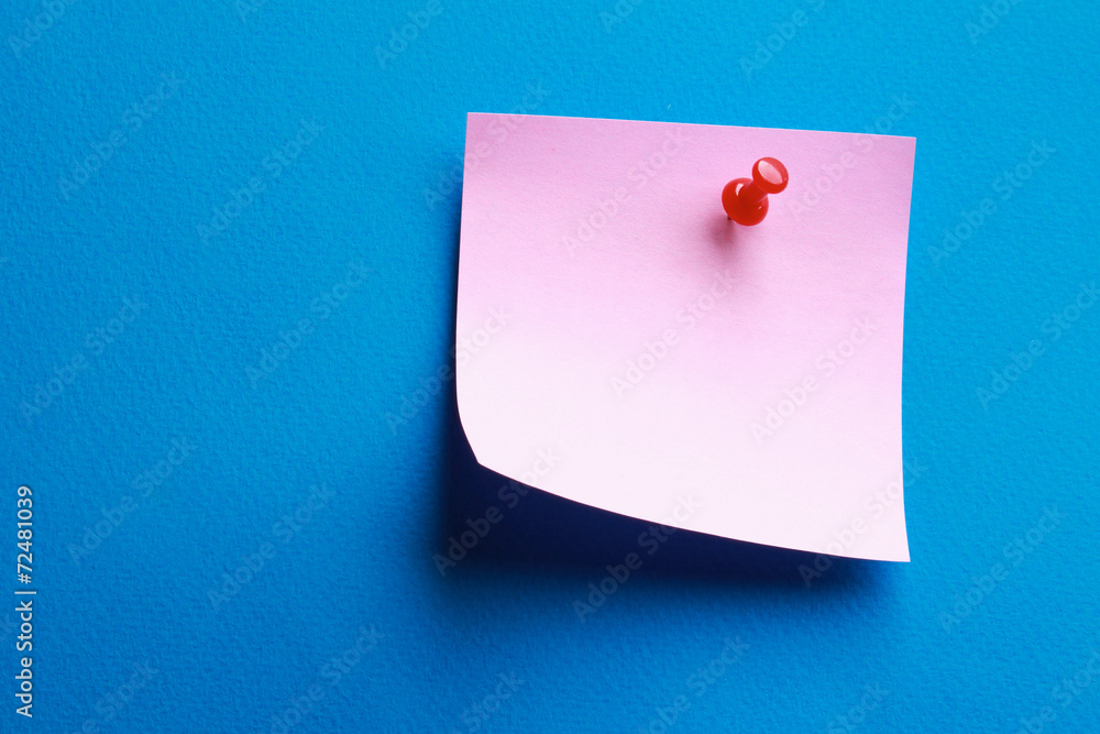 A pink memo note with a red pin on blue