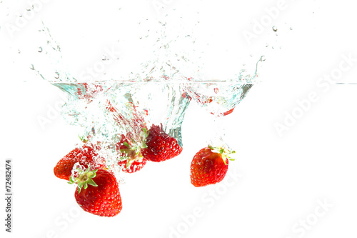 Strawberry dropped into water splash on white