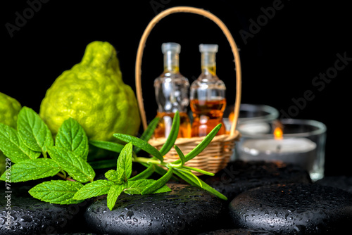 Aromatic spa of bottles essential oil in basket, fresh mint, ros