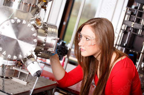 Female scientist looking to the laser deposition chamber photo