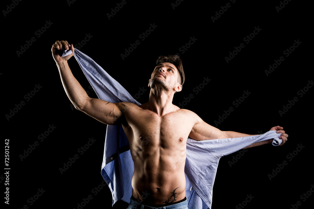 Handsome muscular shirtless young man holding t-shirt Handsome muscular shirtless young man holding t-shirt