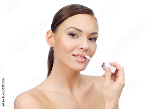 Pretty young woman applying lipstick