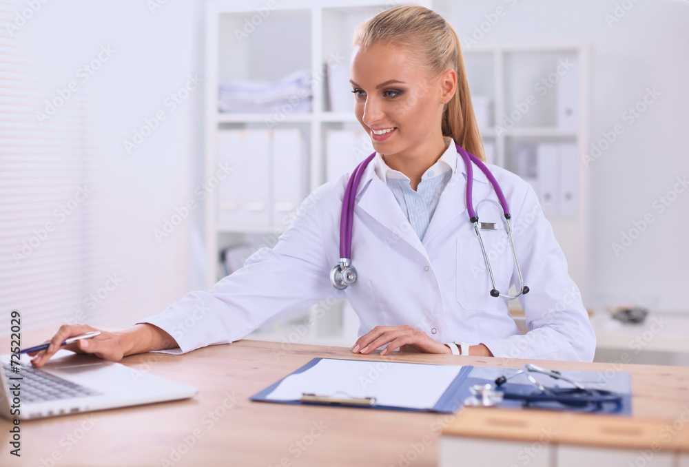 Beautiful young smiling female doctor sitting at the desk and Beautiful young smiling female doctor sitting at the desk and