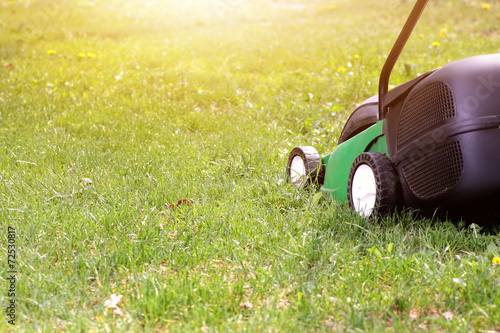 electric lawn mower on a green grass