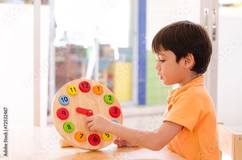 Little boy learning time with clock toy of montessori 