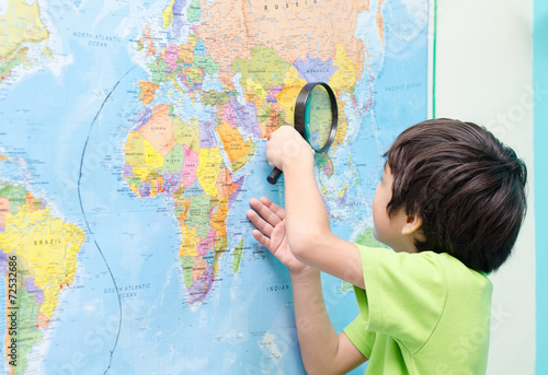 Little boy using magnify looking on map