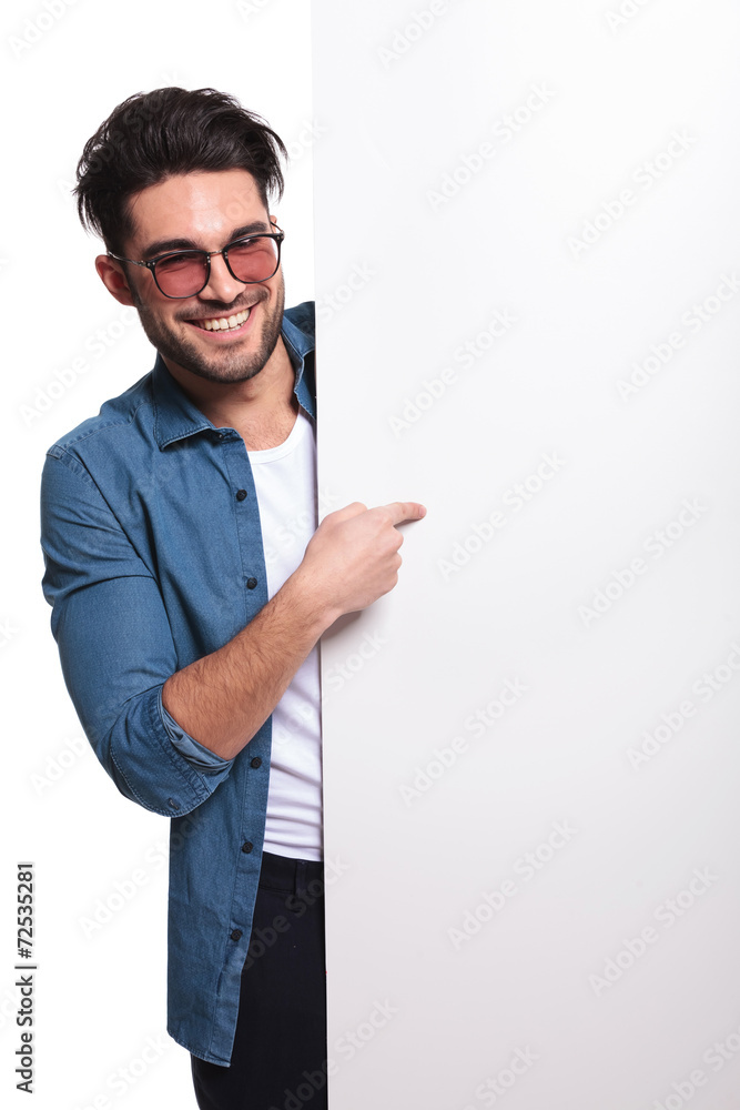 young casual man pointing to a empty board young casual man pointing to a empty board