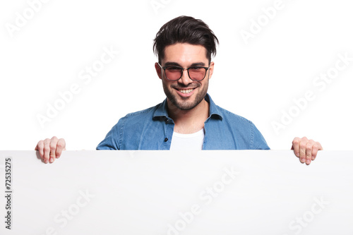 Happy casual man holding a white board