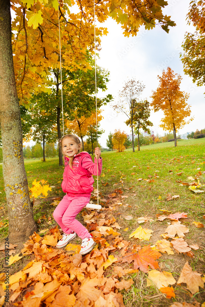 Girl sits on swings holding the ropes in park Girl sits on swings holding the ropes in park