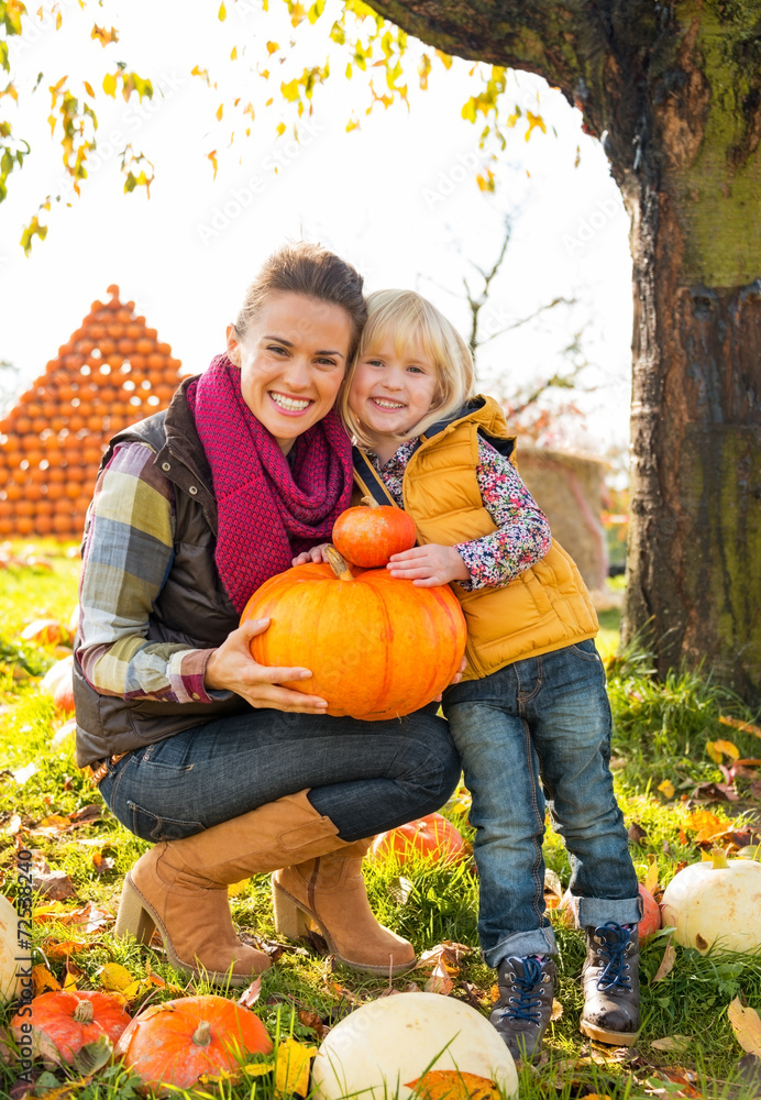 Fototapeta premium Portrait of happy mother and child holding pumpkin