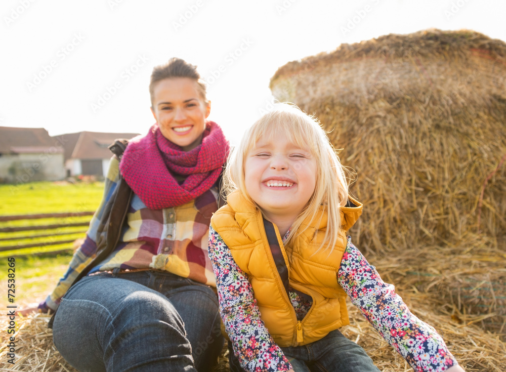 Portrait of smiling mother and child sitting on haystack Portrait of smiling mother and child sitting on haystack