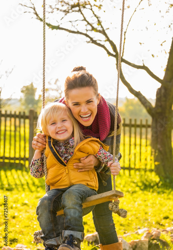 Portrait of smiling mother and child on swing