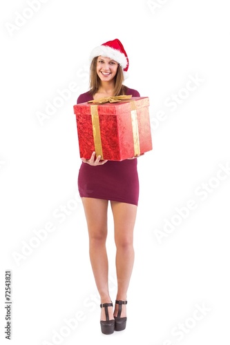 Festive brunette smiling at camera offering gift