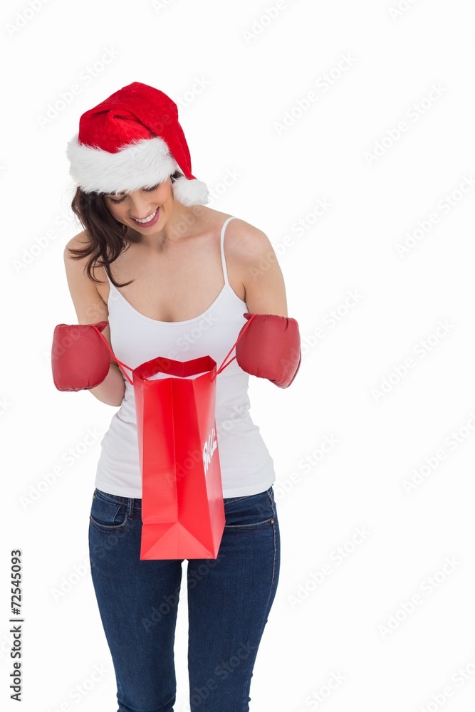 Happy brunette in boxing gloves looking in shopping bag Happy brunette in boxing gloves looking in shopping bag