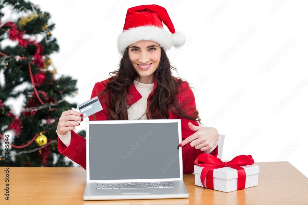Festive brunette shopping online with laptop and pointing screen Festive brunette shopping online with laptop and pointing screen