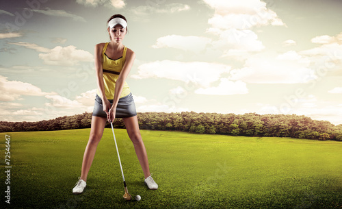 Golf player woman putting ball into hole on green field