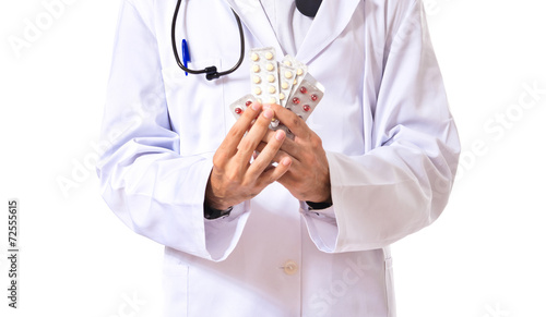 Surprised doctor holding pills over white background