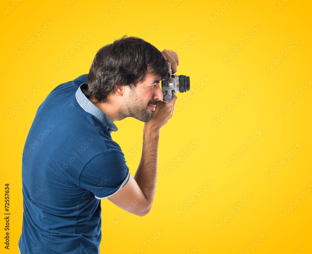 Man photographing over yellow background Man photographing over yellow background