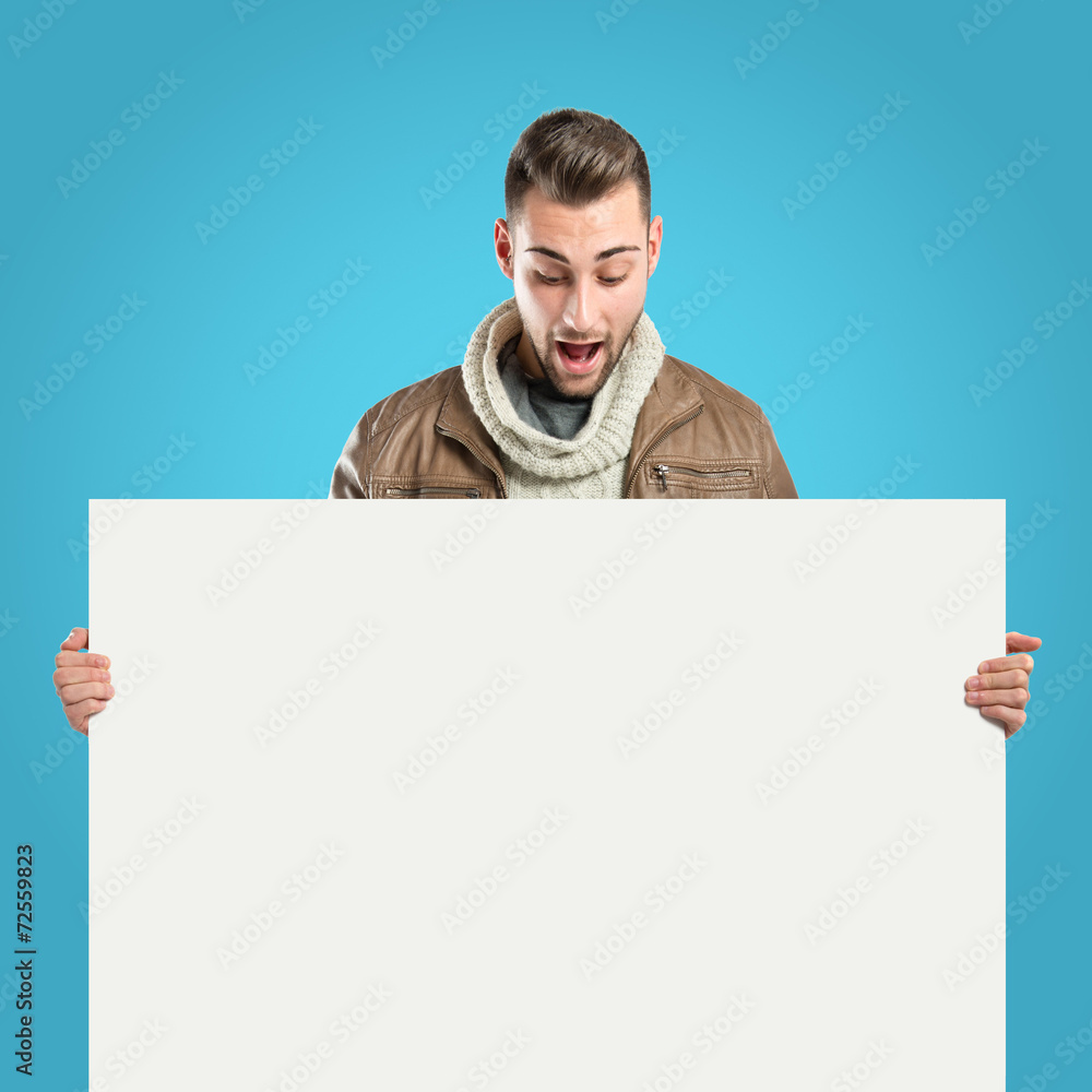 handsome man holding an empty cardboard over blue background handsome man holding an empty cardboard over blue background