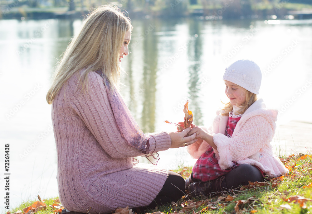 Fototapeta premium Little girl with her mother on the autumn lake