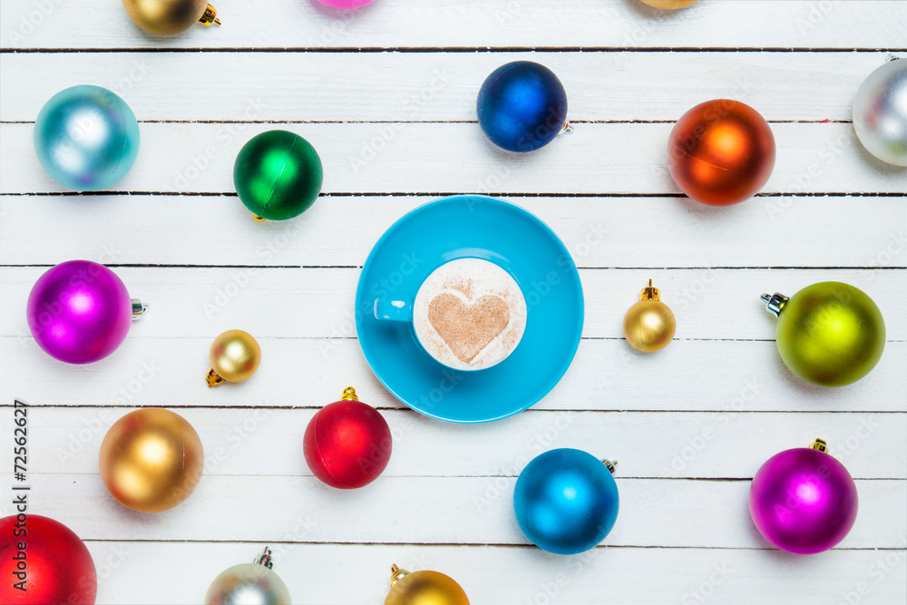 Coffee cup and christmas balls on white background.