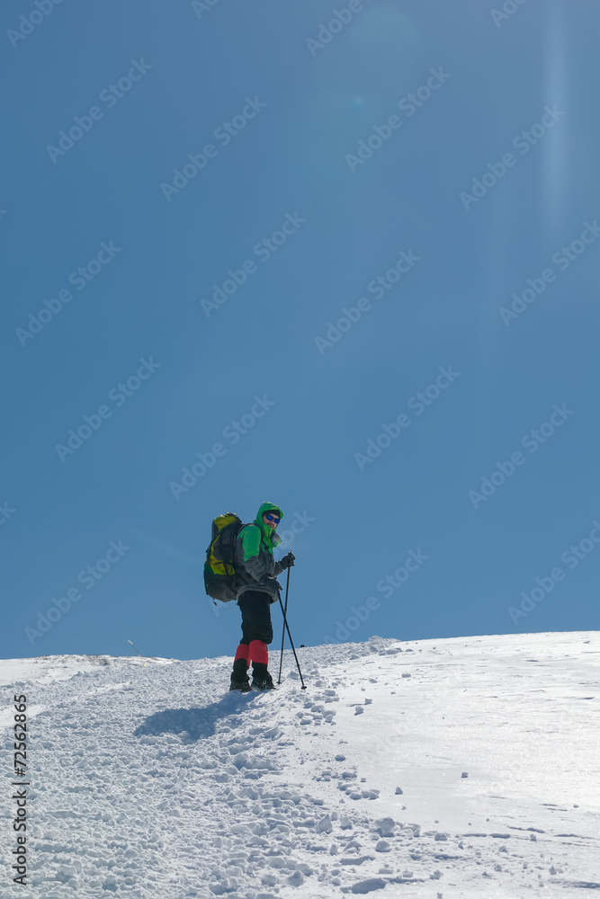 Hiker in winter mountains on sunny day