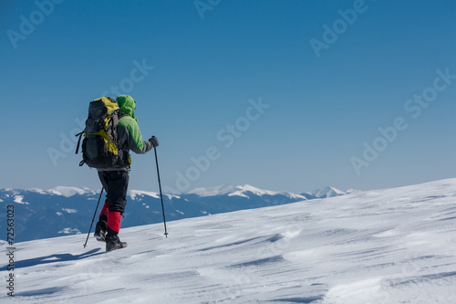 Hiker in winter mountains on sunny day