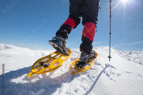 Hiker snowshoeing in winter mountains during sunny day photo