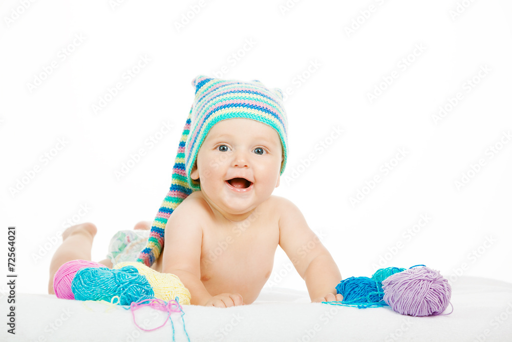 Caucasian cute boy in funny colorful hat between balls of yarn Caucasian cute boy in funny colorful hat between balls of yarn