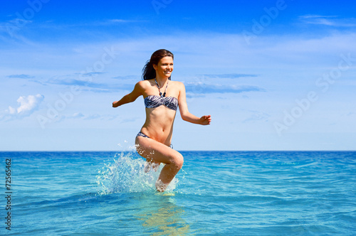 Young woman running through the sea water
