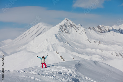 Hiker posing at top of snowy mountain during sunny day © Maygutyak