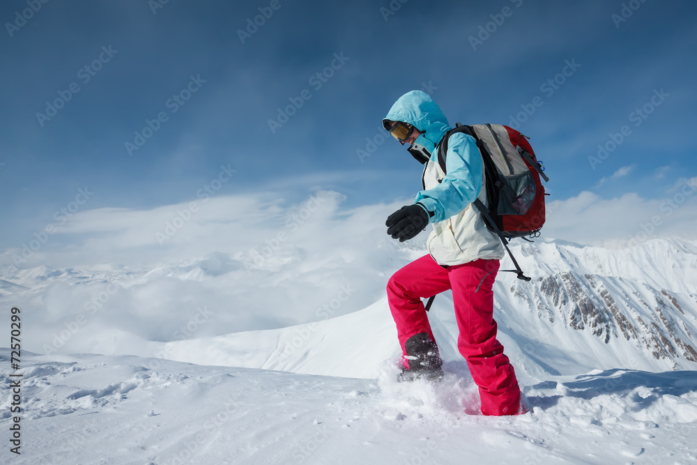 Hiker posing at top of snowy mountain during sunny day