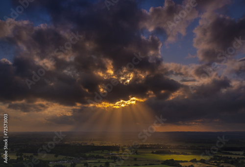Crepuscular rays of sunlight shine onto fields in Dorset