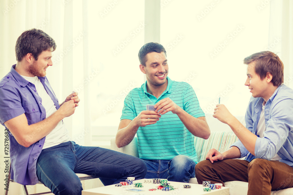 happy three male friends playing poker at home