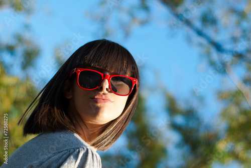 Teenage girl with sunglasses under the trees