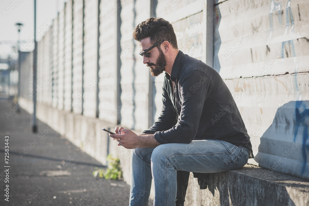 Obraz premium young handsome attractive bearded model man using smartphone
