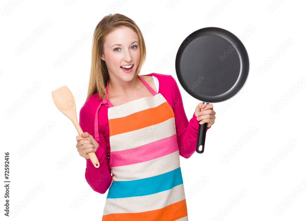 Housewife hold up with pan and wooden spatula Housewife hold up with pan and wooden spatula