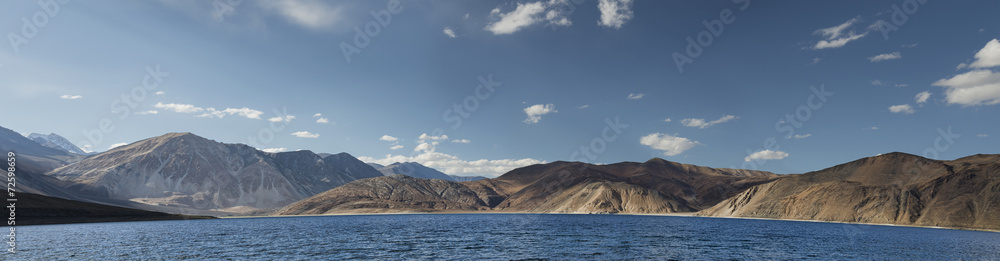 Deep blue mountain lake among hills panorama