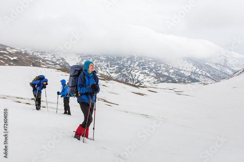 Group of hikers in winter mountains on cloudy day
