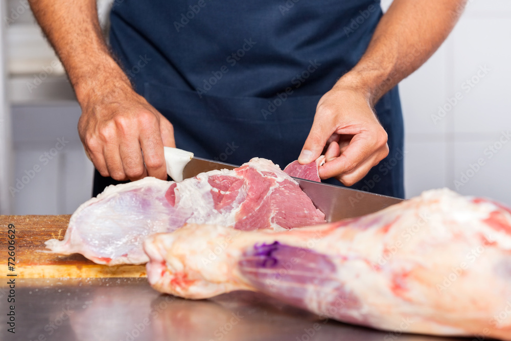 Midsection Of Male Butcher Cutting Raw Meat
