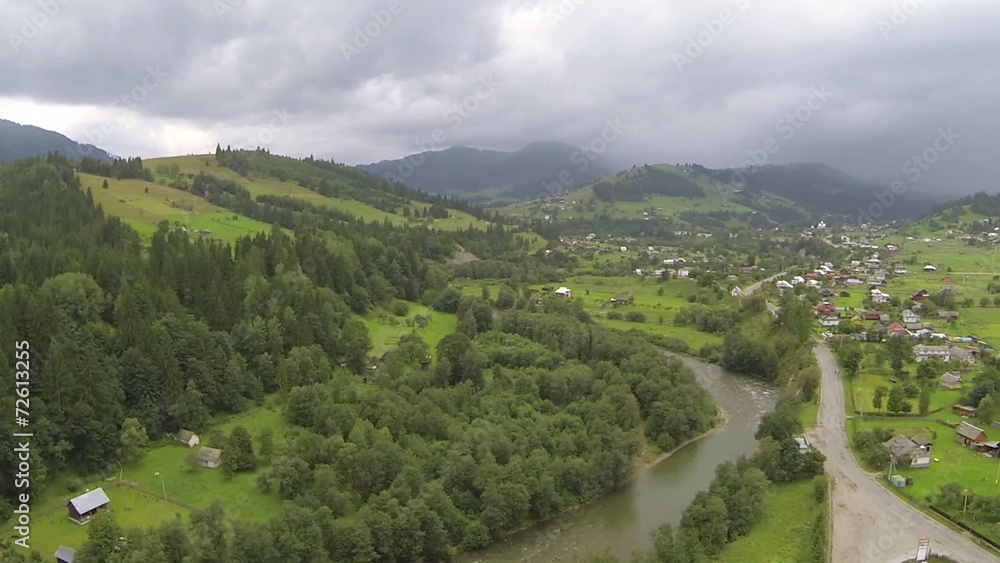 green valley with settlement in mountains. Aerial cloudy day green valley with settlement in mountains. Aerial cloudy day