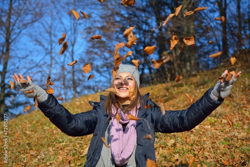 Beautiful girl drop up leaves in autumn forest